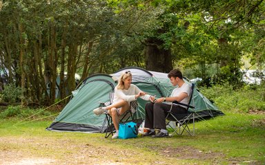 Two people sitting outside in front of a tent