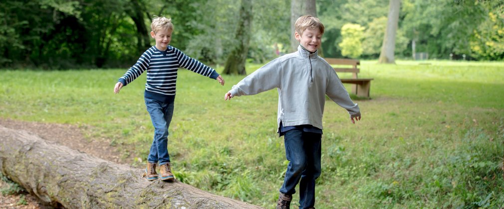 Children playing on a log in a forest meadow