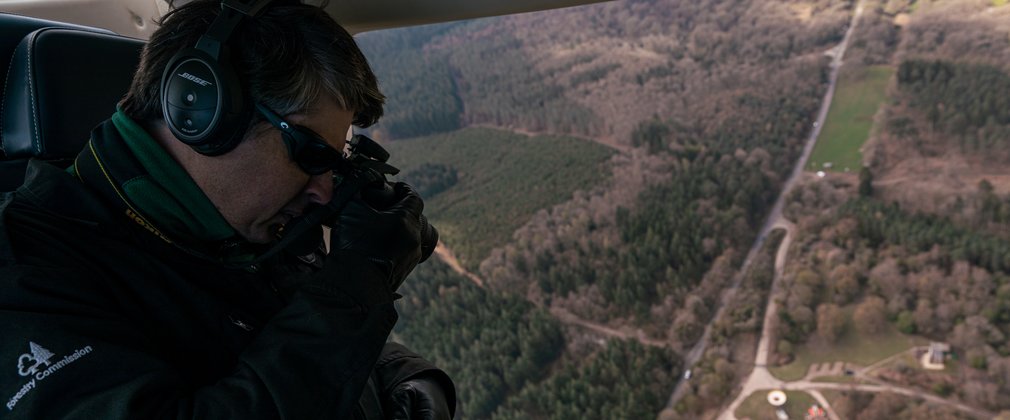 Man doing an aerial survey of the forest from a helicopter