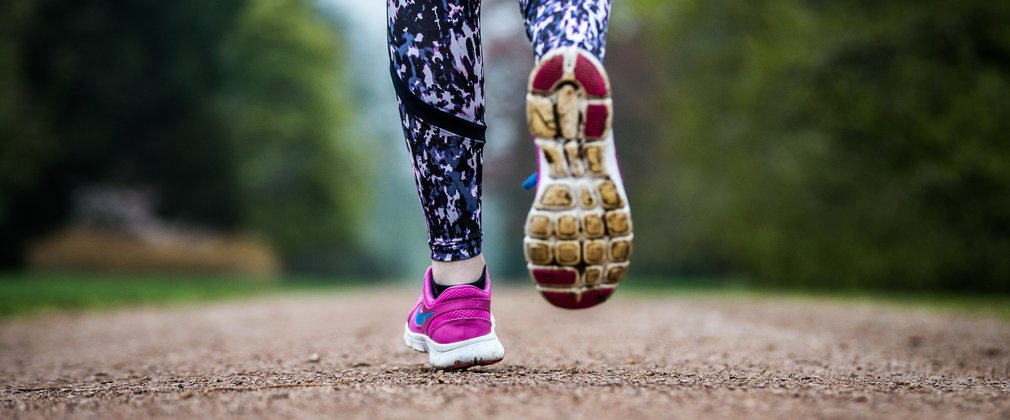close up of trainers running along a brown smooth stone path.