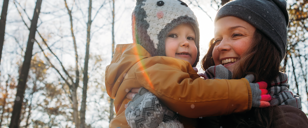 smiling woman holding toddler with winter hats