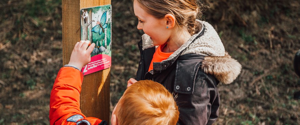 Two children looking at a gruffalo orienteering marker post