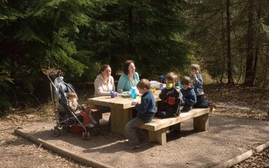 Family sat on a picnic bench enjoying a picnic