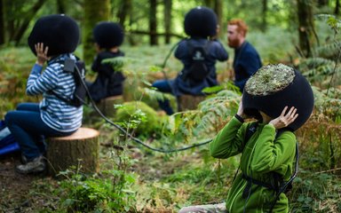 People sitting on logs in the forest with VR headsets