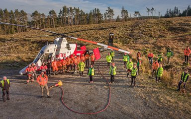 Staff standing by helicopter in forest clearing