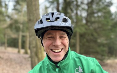 man in cycling helmet and green jacket in a forest