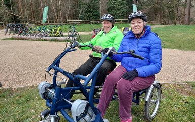 two people on an adapted cycle in a forest setting