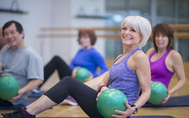 A group of older adults doing pilates with weighted balls