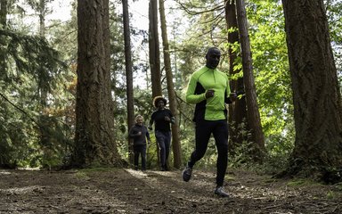 three people running in forest