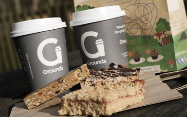 Two Grounds coffee cups with some food in front of it