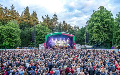 Forest Live stage surrounded by trees and showing a large crowd.