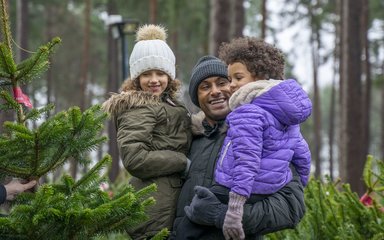 Family picking christmas tree in forest 