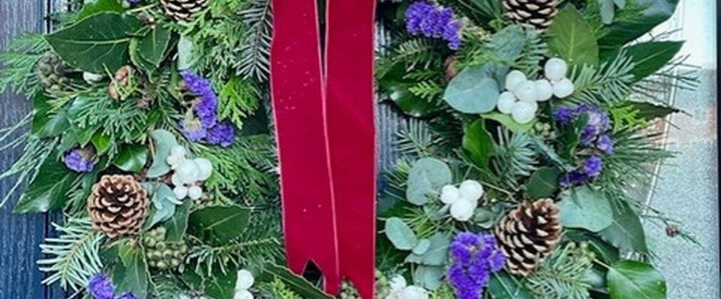 A festive wreath with greenery and a red bow on a door