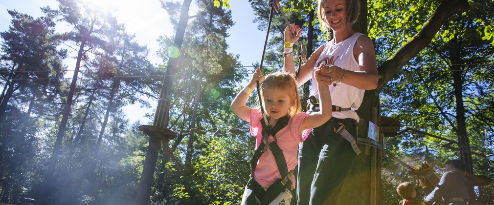 Woman and child in harnesses on adventure climbing trail