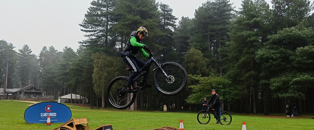 Boy jumping over a ramp on a bike in a tree-lined field