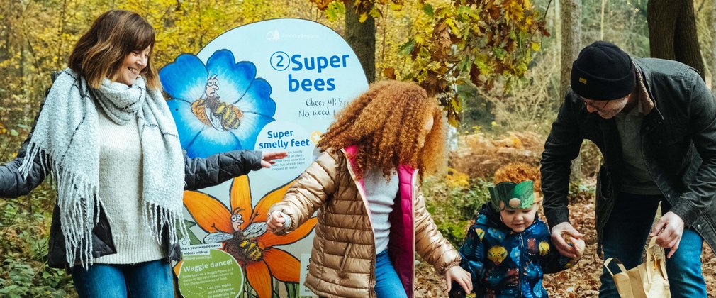 Family in front of a Superworm panel pretending to be a bee