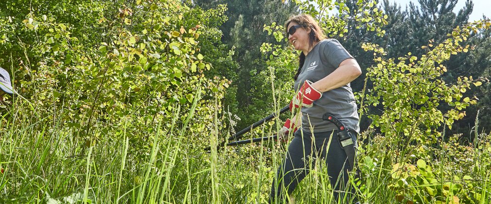 Woman volunteering, clearing forest shrubs