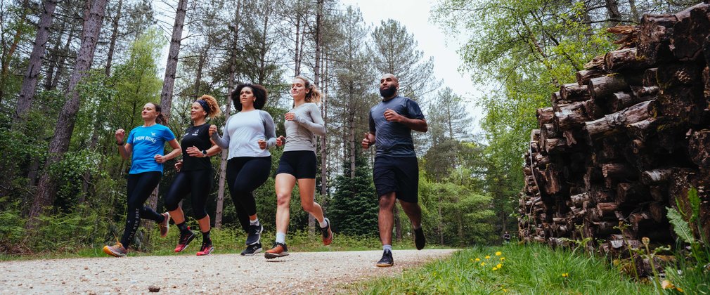 Five people running through forest