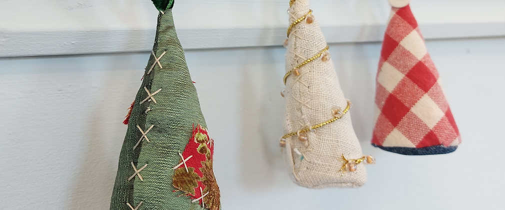 A set of three hand made cloth Christmas decorations hand from gold hooks. They look like colourful Christmas trees made from scraps of material with lovely sewed detail.