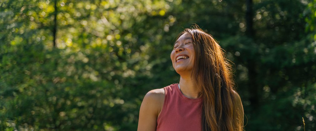 woman laughing looking up in a forest