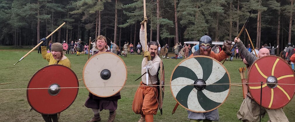 Vikings with shields in front of a forest