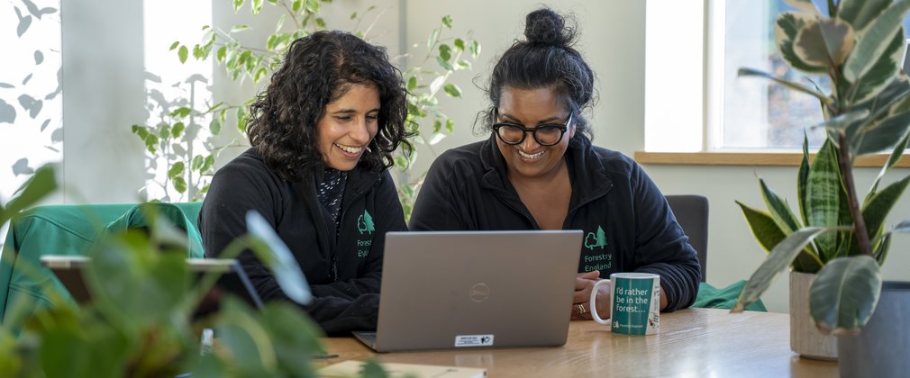 Two women smiling looking at a website in an office