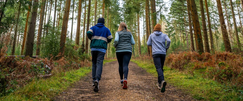 Three people running in a forest