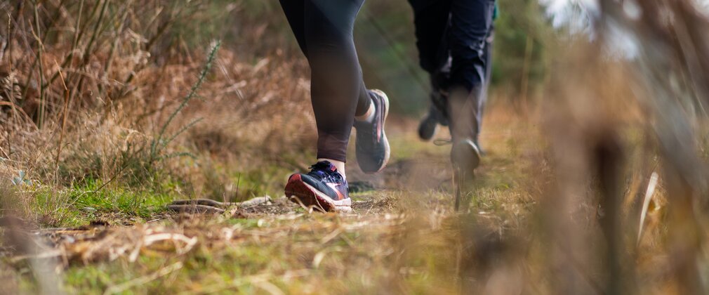 Two runners close up of legs running through a forest path