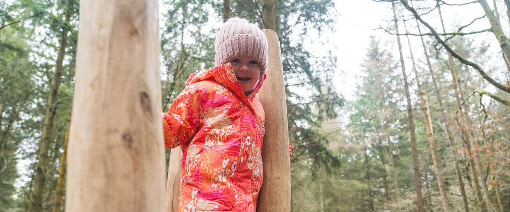Girl enjoying play equipment in winter woods