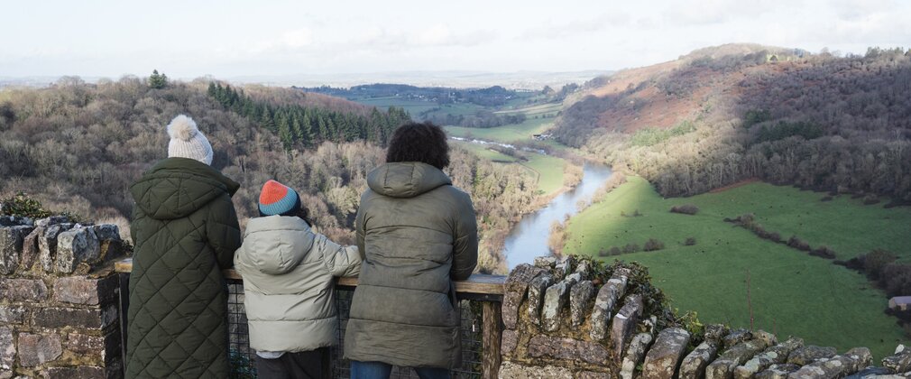A family dressed in winter clothing looking out from Symonds Yat Rock viewpoint across the Wye Valley