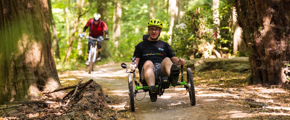 A recumbent trike rider on a forest cycle trail