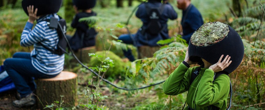 People sitting on logs in the forest with VR headsets