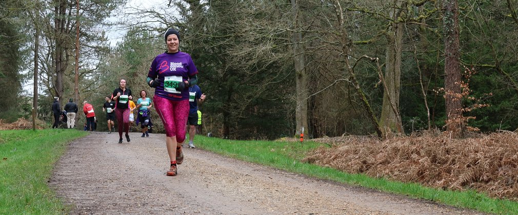 A person running on a trail through the forest.
