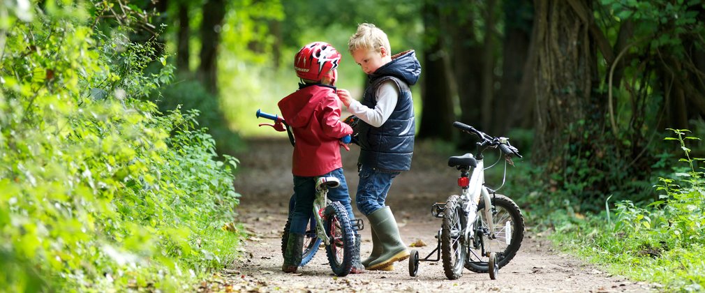 Two small boys learning to cycle in the woods 