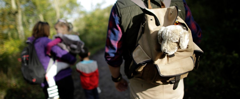 A family with backpacks walking down a forest track