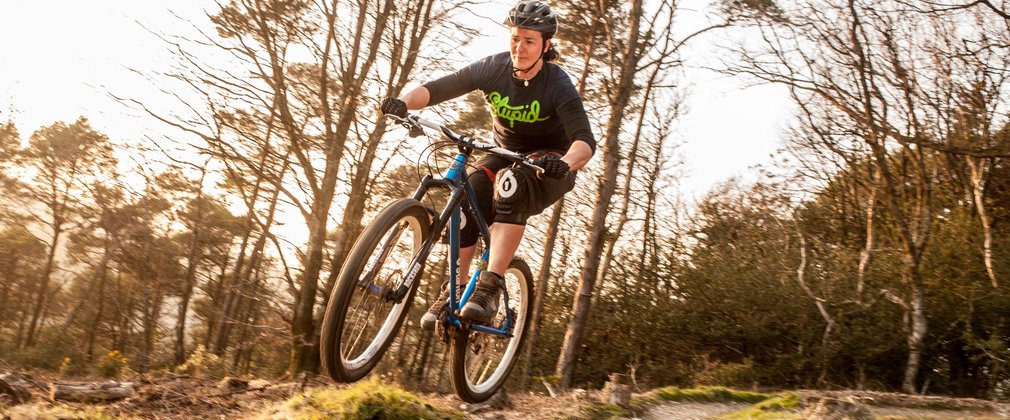 Lady jumping off a jump on a mountain bike track