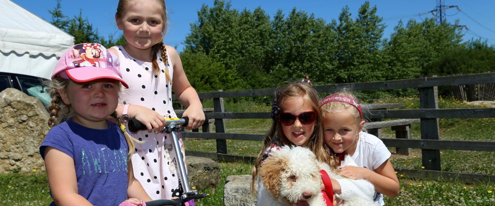 little girls having fun in the woods with their scooters and dog