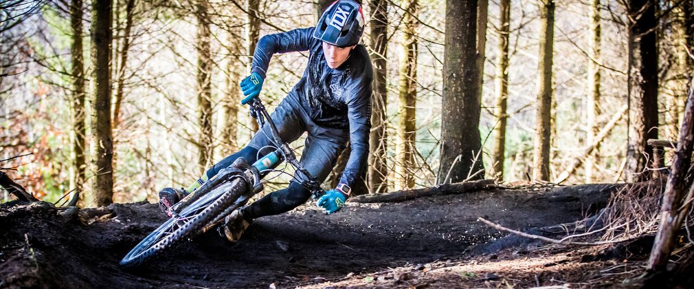 Man on mountain bike going round tight corner on trail in the forest
