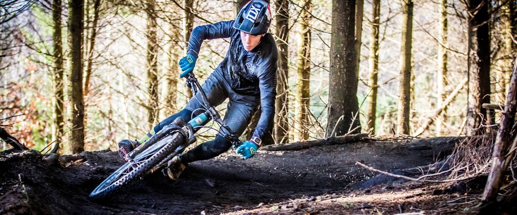 Man on mountain bike going round tight corner on trail in the forest 