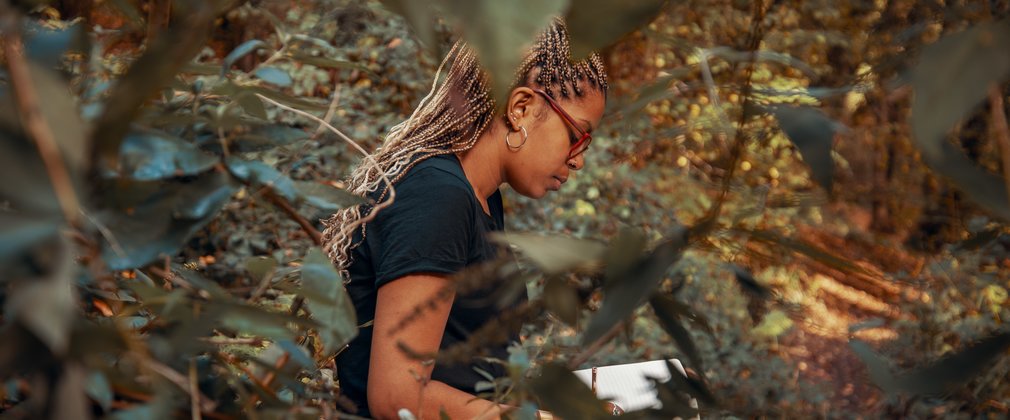 Woman writing on a notepad in the forest