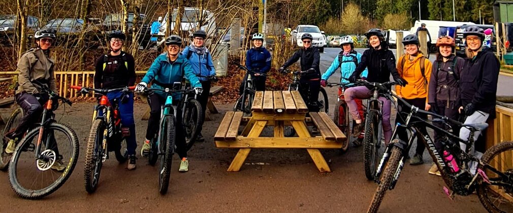 A group of smiling women on their mountain bikes posing for a photo.