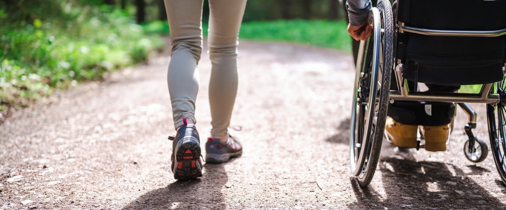 A women walking next to a man in a wheelchair on a forest track