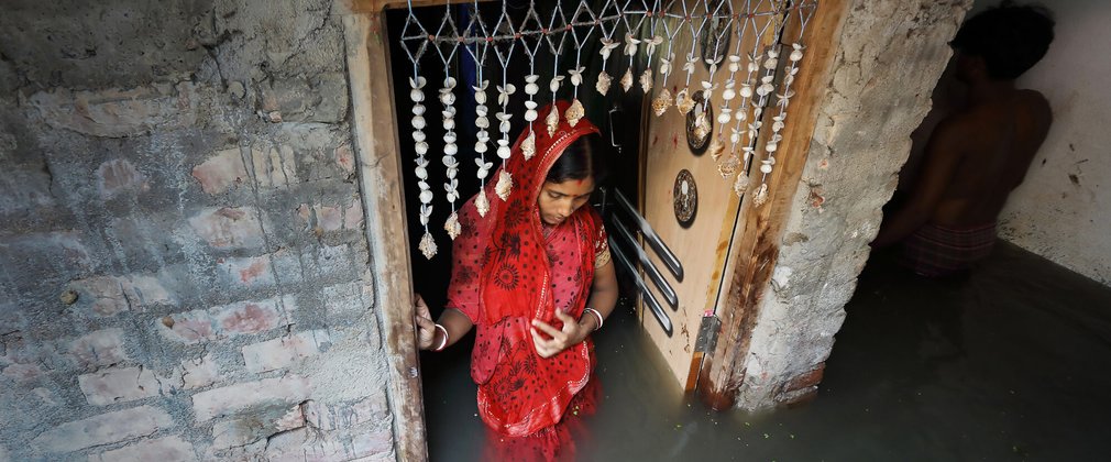Indian woman in red wedding gown walking in flooded home
