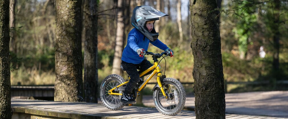 Child riding a wooden bridge feature in a skills area