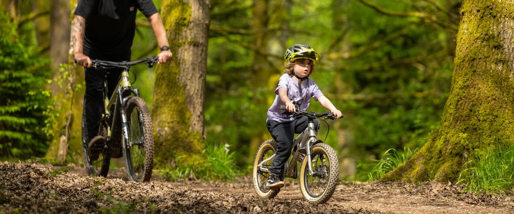 Man and child riding bikes in a forest