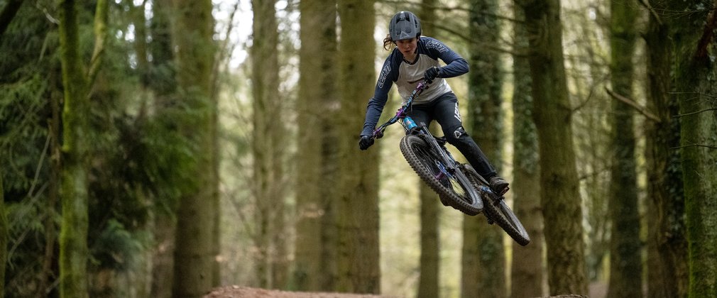 Cyclist jumping on a mountain bike trail in the Forest of Dean
