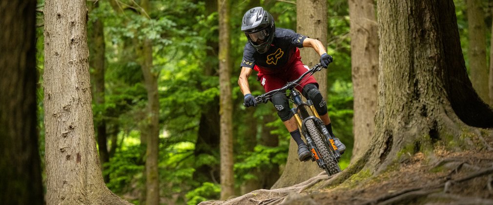 Mountain biker riding over roots wearing a full face helmet