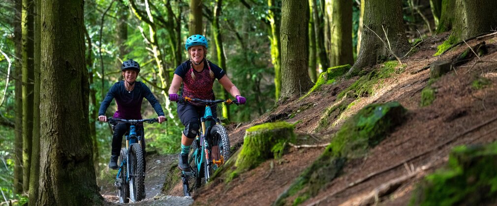 Two women riding mountain bikes in a forest