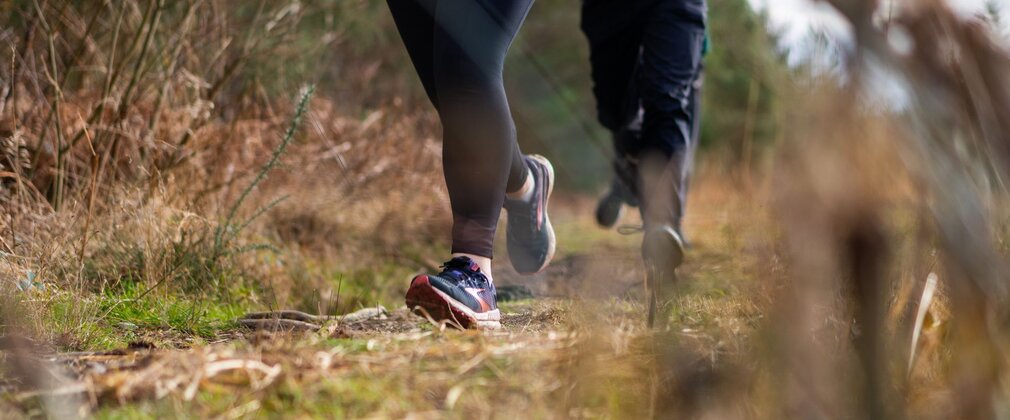 Close-up of two pairs of feet running long a grassy surface