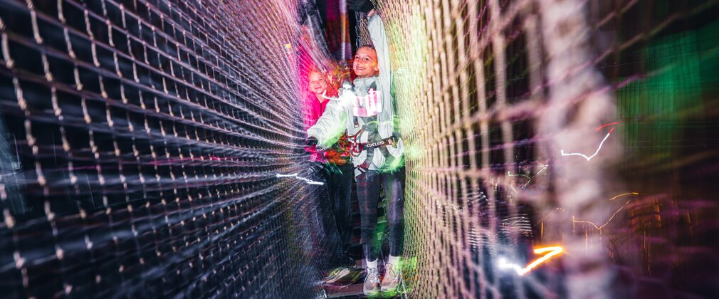Children walking across a rope bridge in the dark